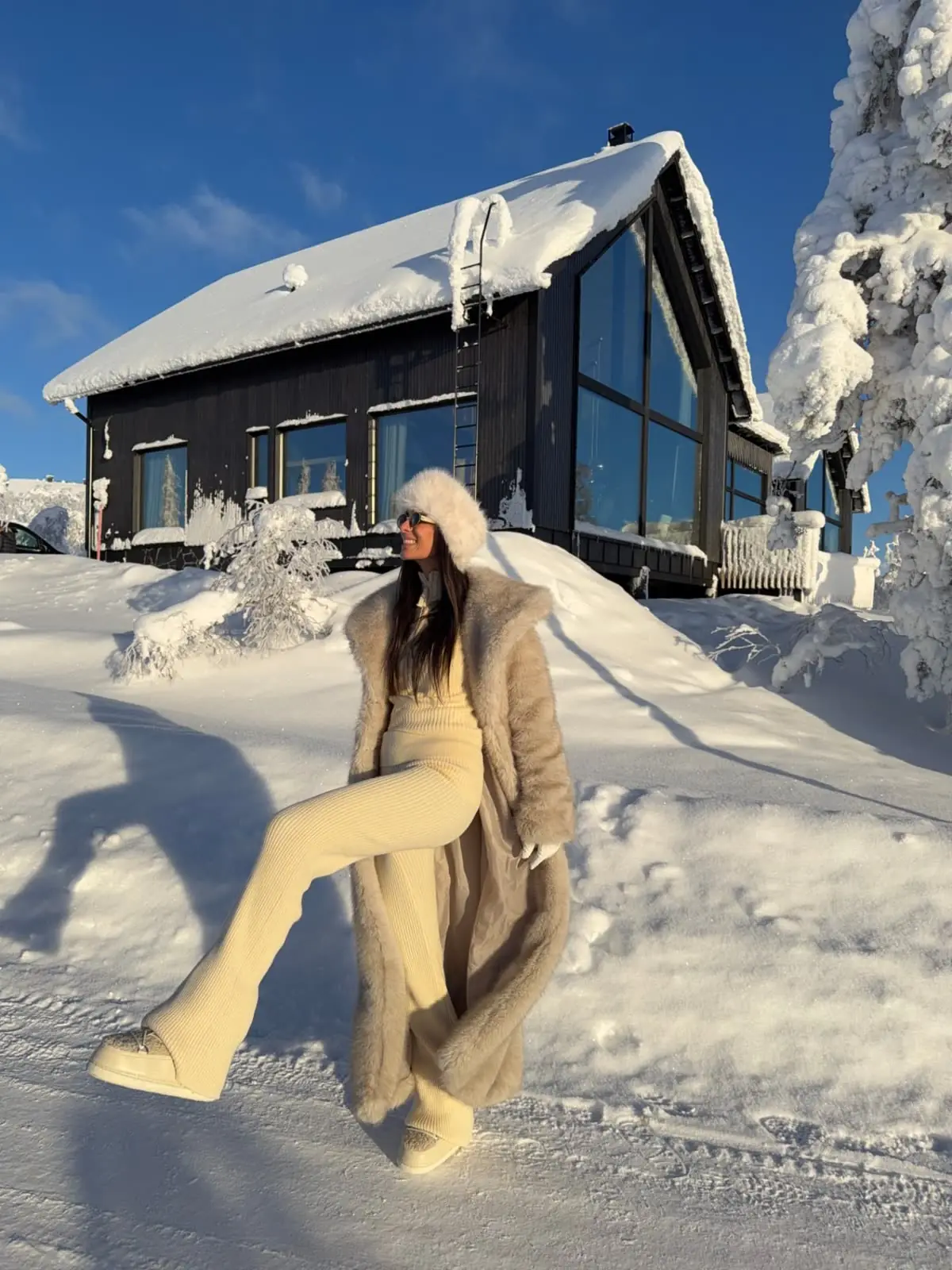 Aura guest in a light fur coat in the snow outside the chalet